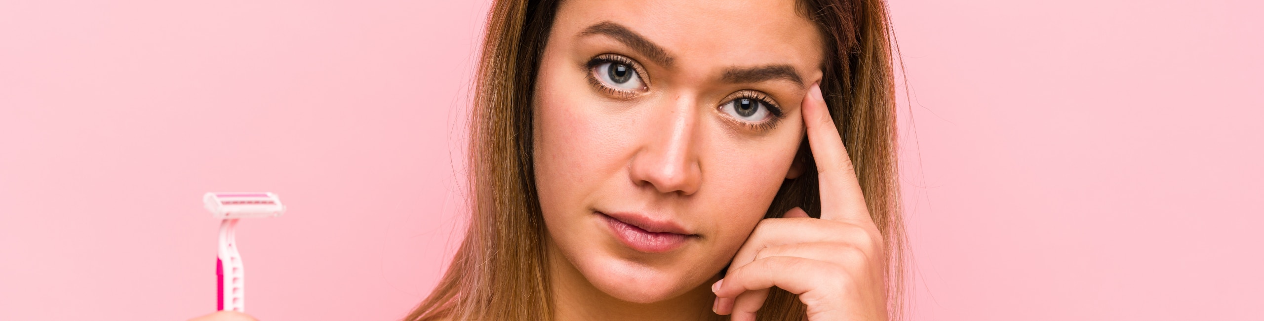 Junge Frau, die ein Rasiermesser in der Hand hält und besorgt aussieht